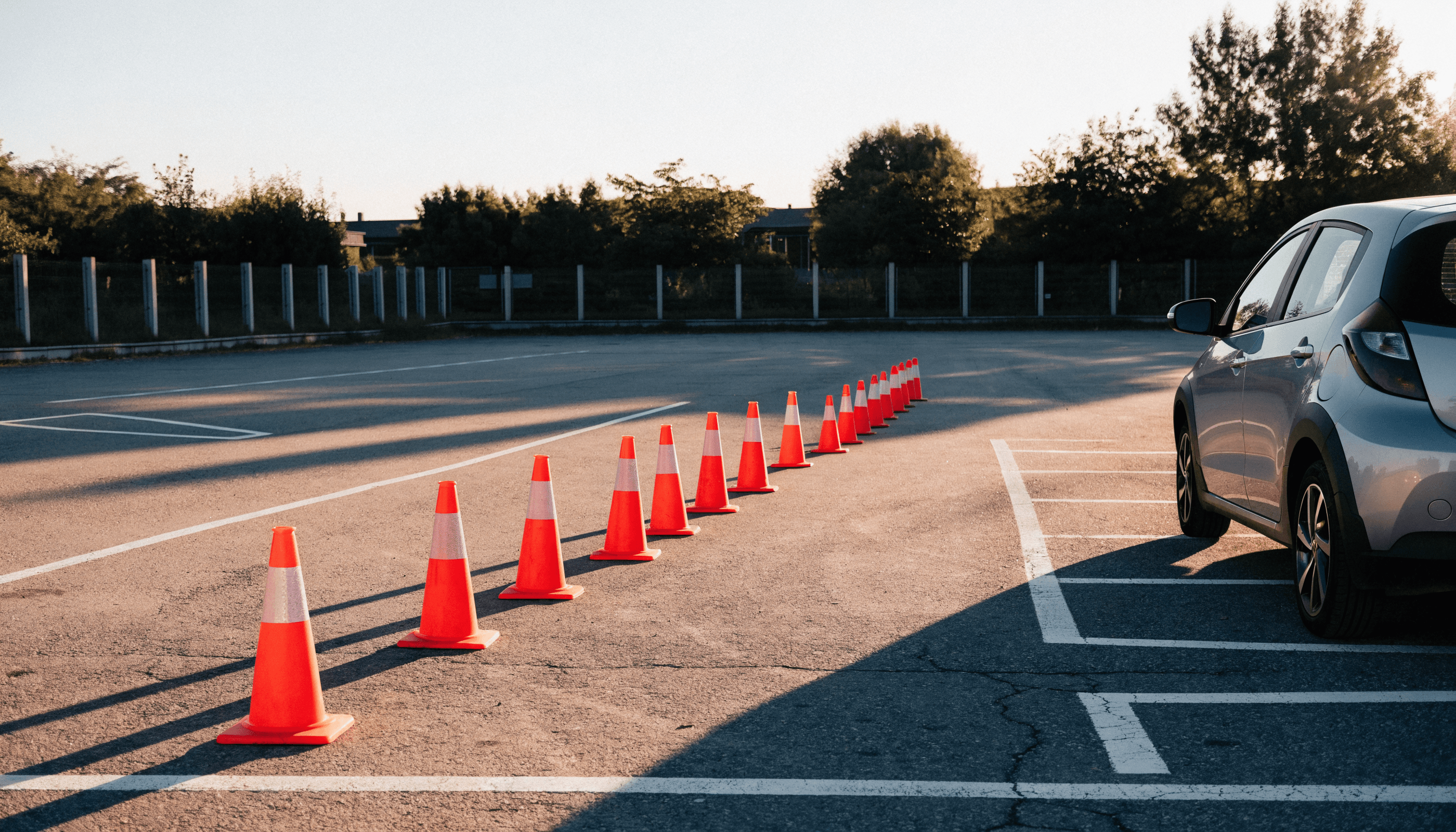 Übungsplatz einer Fahrschule mit aufgestellten Pylonen und einem geparkten Schulungsfahrzeug.